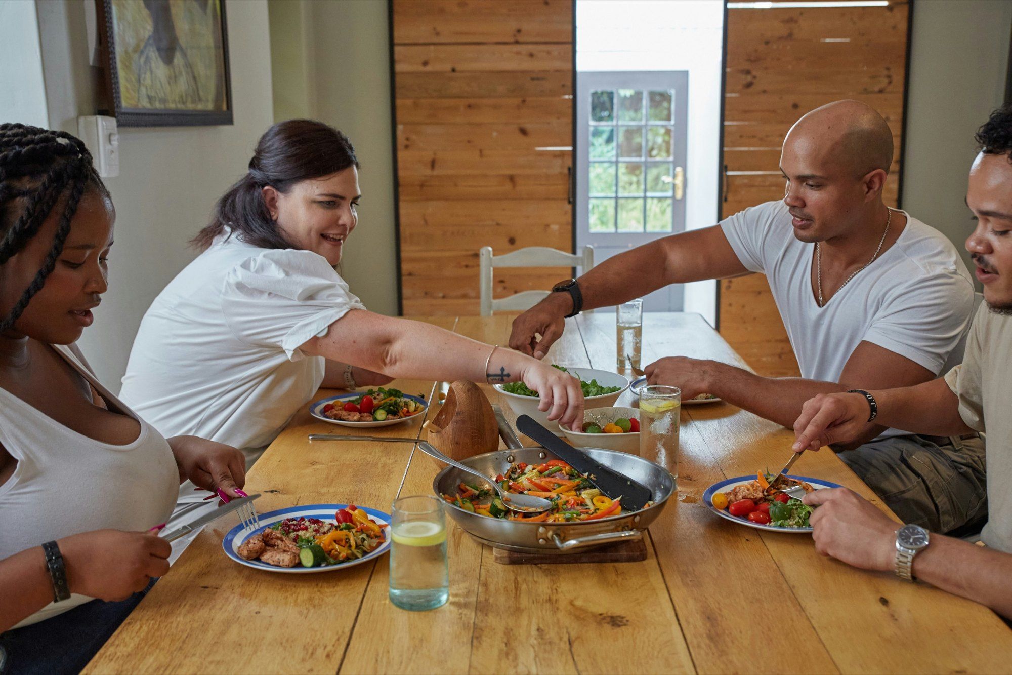 Friends sharing lunch at a wooden table, with glasses of water.
